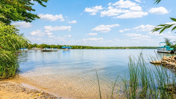 A calm lake with boats, clear water, and a sandy shore. - Private Retreat Near Interlochen Arts| Green Lake (Interlochen)
