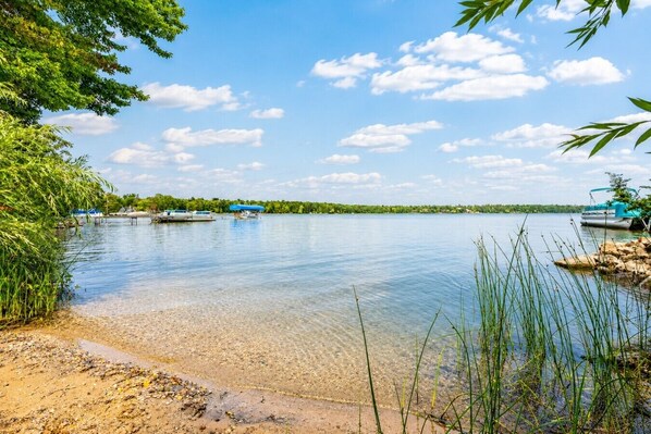 Un lac paisible, avec des bateaux, une eau claire et une rive sablonneuse.