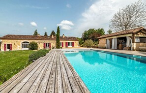 A swimming pool with a wooden deck, stone buildings, and a tree. - Gorgeous home in Villamblard (Villamblard)