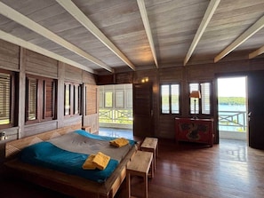 Ein Zimmer aus Holz mit einem Bett, Bänken und Blick durch eine Tür.