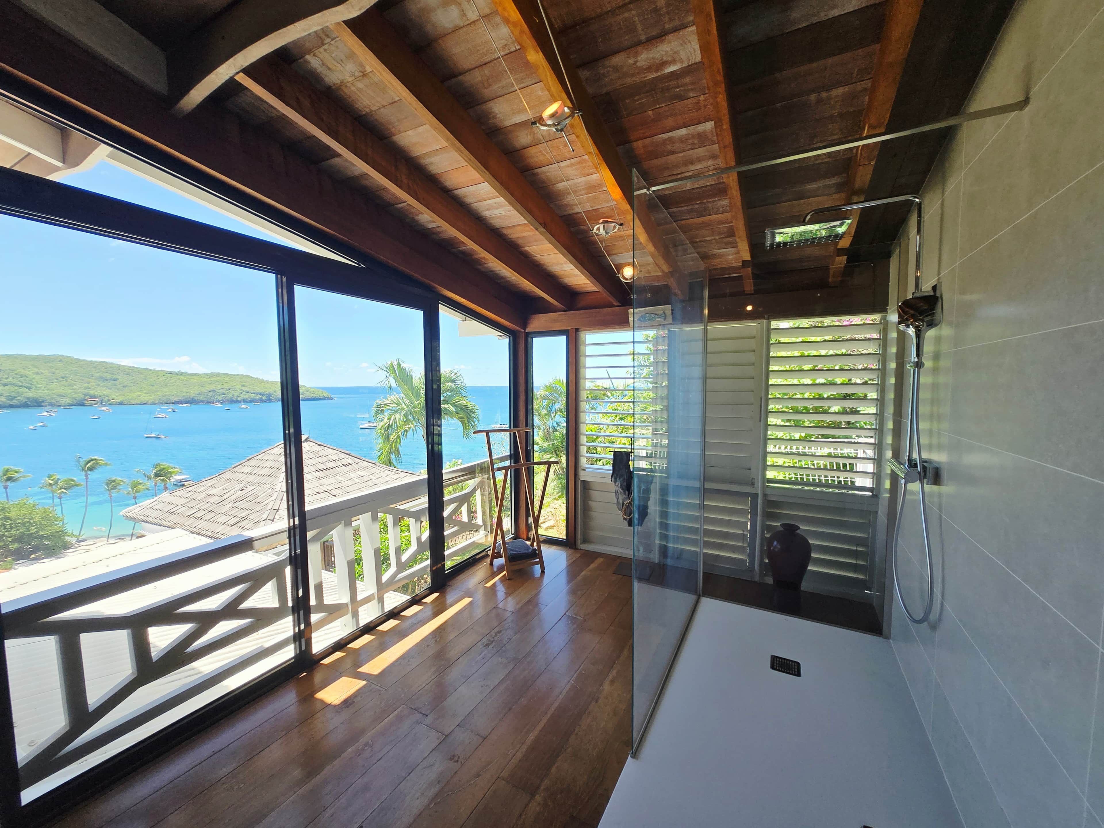 Ein geräumiges Zimmer mit einer großen Glasdoor, die auf einen Balkon mit Blick auf die malerische Küstenlandschaft führt.