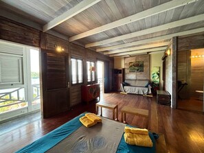 Une pièce avec un plancher en bois, un lit avec une literie bleue, un banc en bois et une petite table.
