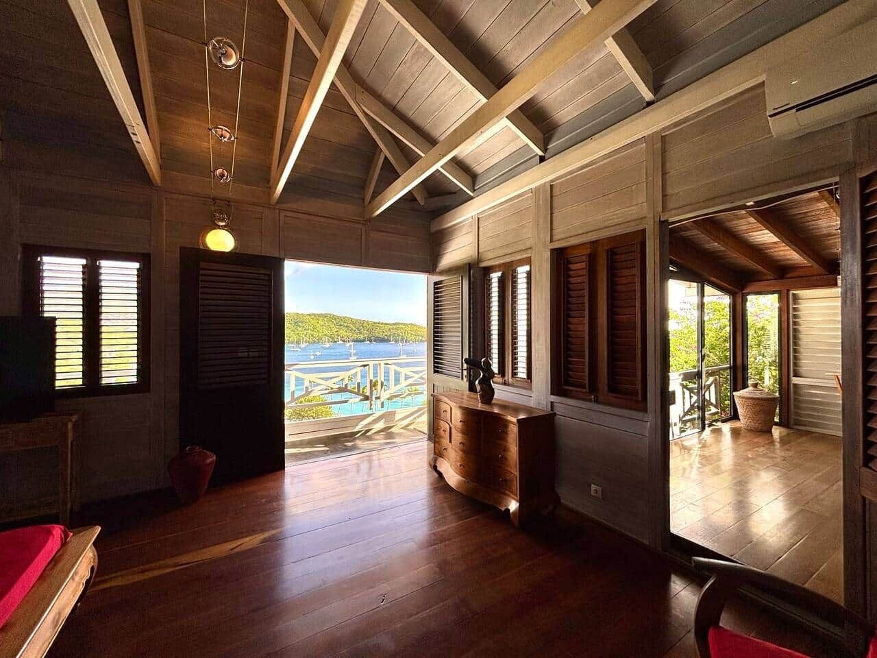 Une pièce spacieuse avec un plancher en bois, de grandes fenêtres et une vue sur un pont et l’eau.