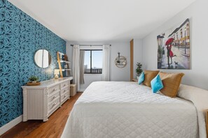 Ein Schlafzimmer mit Bett, Schminktisch und einem Fenster mit Vorhängen.