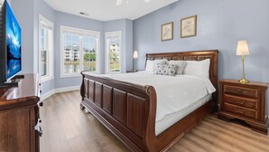 A bedroom with a large bed, two bedside tables, a ceiling fan, and a window with a view of buildings. - Magnolia Pointe Magnolia Lake 4812-102 | Lakeview Myrtlewood Retreat Near Beach & Golf (Myrtle Beach)
