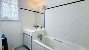 A bathroom with a bathtub, a sink, and a mirror.