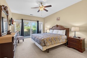 A bedroom with a bed, nightstands, a dresser, a ceiling fan, and a view through the glass doors. - World Tour 1033-102 in River Oaks | World Tour Golf Retreat Near Beach & Dining (Myrtle Beach)