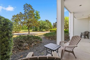 A patio with outdoor furniture, a view of a road, and a tree. - World Tour 1033-102 in River Oaks | World Tour Golf Retreat Near Beach & Dining (Myrtle Beach)