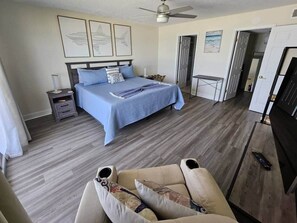 Un dormitorio con cama, mesitas de noche, ventilador de techo y vistas a la playa.