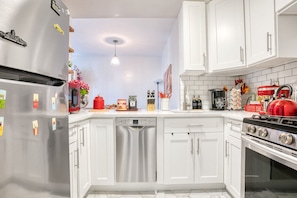 A modern kitchen with white cabinetry, stainless steel appliances, and a red kettle. - 3BR Brooklyn Flatbush | King Bed, 2 Queens | 5 Min to Kings Theatre (Brookyn)