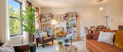 Una sala de estar acogedora con chimenea, estantería y comedor.