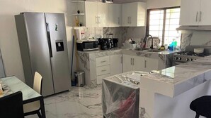 A modern kitchen with a refrigerator, microwave, stove, and marble countertops.
