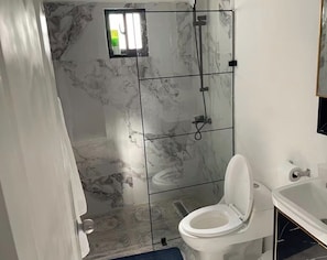 Un baño con ducha, inodoro y lavamanos.
