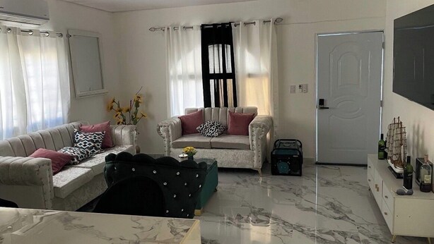 A living room with a sofa, a chair, a coffee table, a TV, and a door.