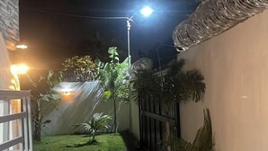 A nighttime view of a narrow pathway flanked by buildings, with a streetlight illuminating the area.