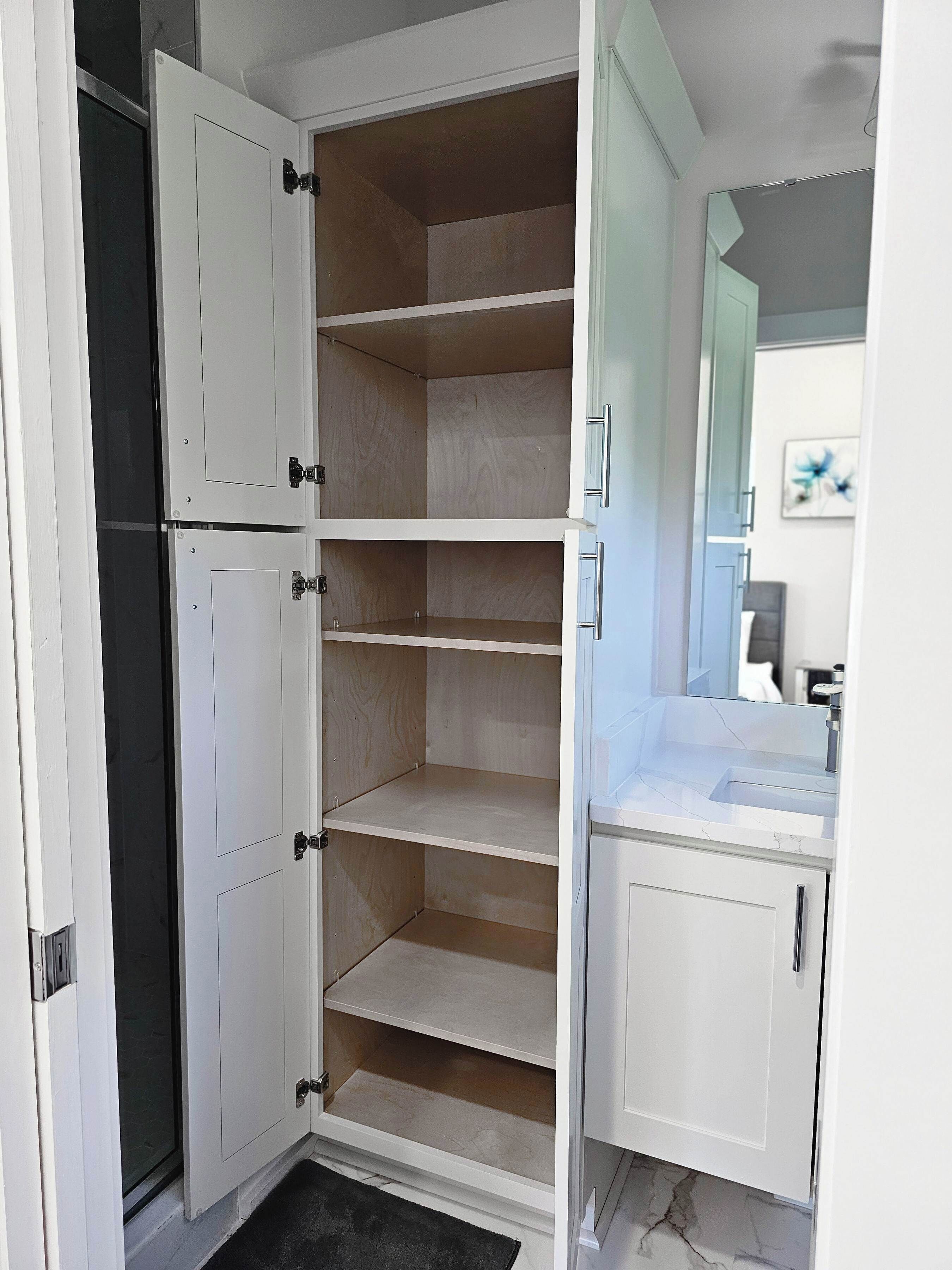 A kitchen with white cabinets, a countertop, and a door leading to another room.
