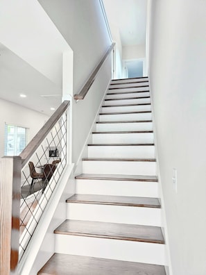 Eine Treppe mit Holzbodenstufen und einem Metallgeländer, die zu einer oberen Etage führt.
