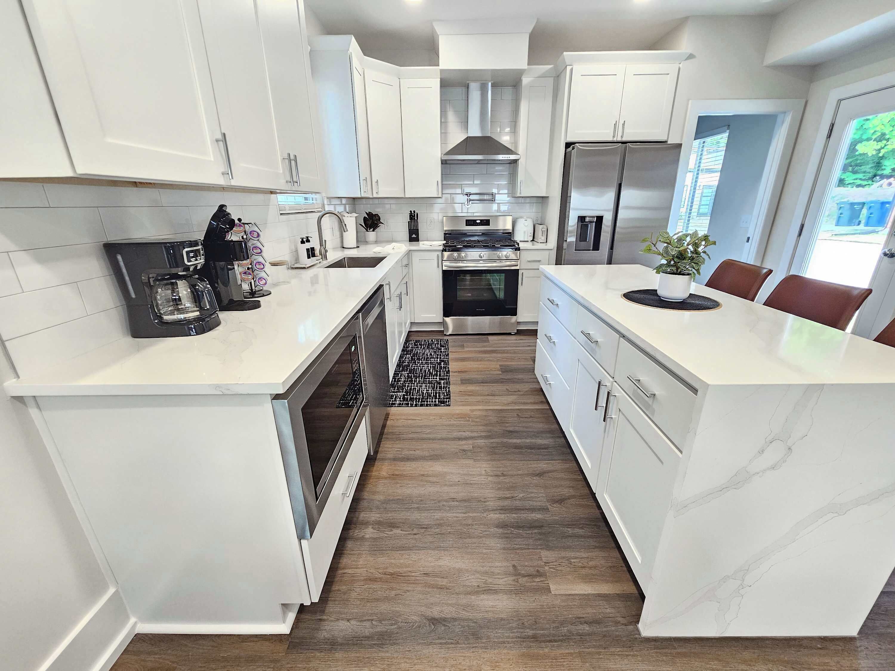 A modern kitchen with white cabinetry, stainless steel appliances, and a central island.