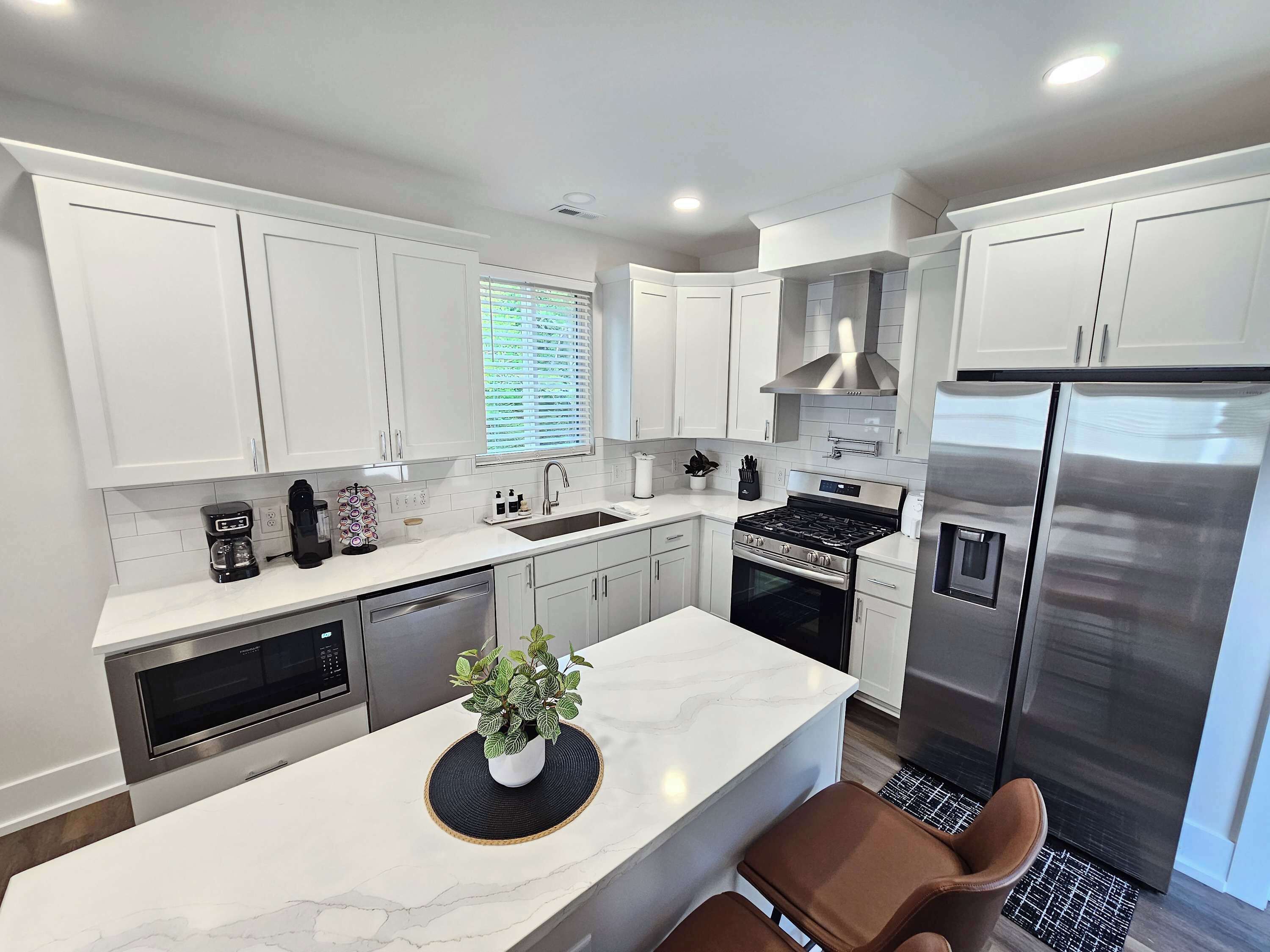 A modern kitchen with white cabinetry, a stainless steel refrigerator, a built-in oven, and a coffee maker.