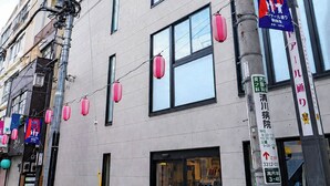 A building with multiple windows, a visible entrance, and a sign with Japanese text. - craft hotel antenna SHINJUKU KOENJI (Tokyo)