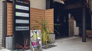 A hotel entrance with a wooden facade, a sign for 'Sunbright Koenji Antenna,' and a 'Step Ahead' sign. - craft hotel antenna SHINJUKU KOENJI (Tokyo)