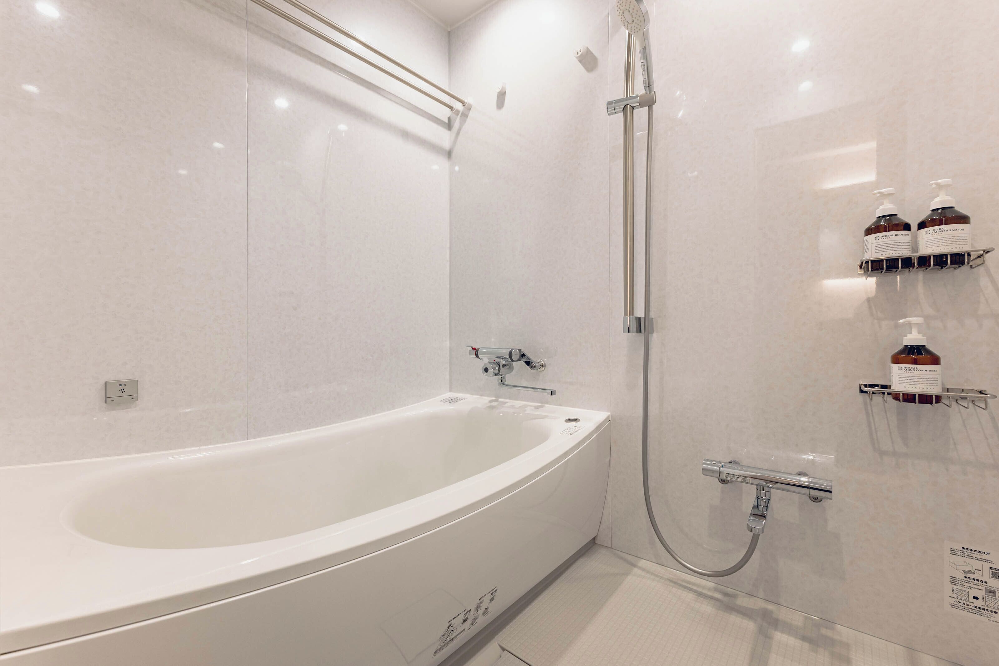 Een moderne badkamer met een wit bad, douche en handdroger.