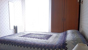 Ein Schlafzimmer mit Bett, Fenster, Tür und Lampe.