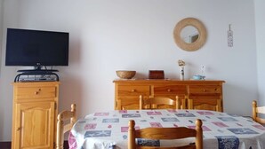 Ein Schlafzimmer mit Fernseher, Holzmöbeln, einem Bett mit gemustertem Überwurf, einem Wandbehang aus Textil und einem an der Wand befestigten Spiegel.