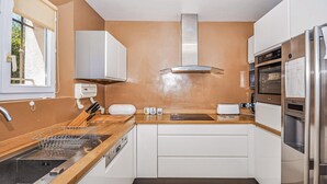A compact kitchen with a sink, stove, and oven, white cabinets, and a window. - Beautiful home in Grasse (Grasse)