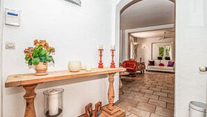 A hallway with a wooden console table, a potted plant, candles, and a lit candle in a glass holder. - Beautiful home in Grasse (Grasse)