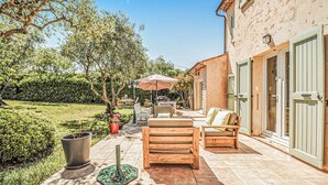 A patio with outdoor furniture, a potted plant, and a wall with a door. - Beautiful home in Grasse (Grasse)