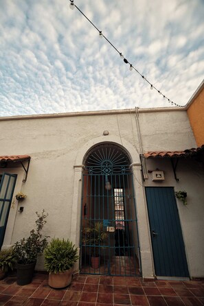 Un bâtiment avec une porte bleue, un portail et des plantes en pot.