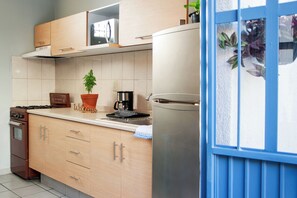 A kitchen with wooden cabinets, a stove, a refrigerator, a coffee maker, and a potted plant. - Casa Arrayán | Downtown Guadalajara | Beautiful Colonial Home with Courtyard (Guadalajara)