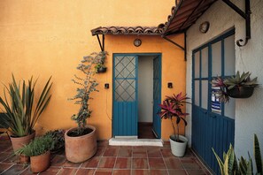 A building entrance with a blue door, potted plants, and a sign on the wall. - Casa Arrayán | Downtown Guadalajara | Beautiful Colonial Home with Courtyard (Guadalajara)