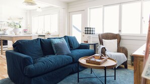 A living room with a blue sofa, a round coffee table, and a wicker chair.