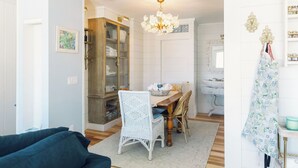 A dining area with a table, chairs, a chandelier, a cabinet, and a coat rack.