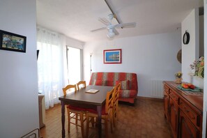 A dining area with a table and chairs, a ceiling fan, a sofa, and a radiator. - T2 cabin for 4 people, terrace, parking near the beach (LE GRAU DU ROI)