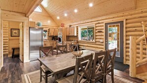 L’intérieur d’une cabane en rondins comprend un coin repas, une cuisine et une grande fenêtre.