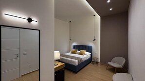 Quarto moderno com cama, mesa de cabeceira, cadeira e guarda-roupa.