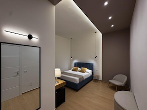 A modern bedroom with a bed, bedside table, chair, and wardrobe. - An oasis of luxury in the heart of Marsala (MARSALA)