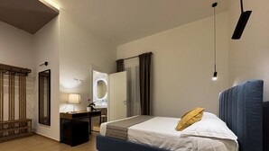 Quarto com cama, mesa de cabeceira, luminária, espelho e janela com cortinas.