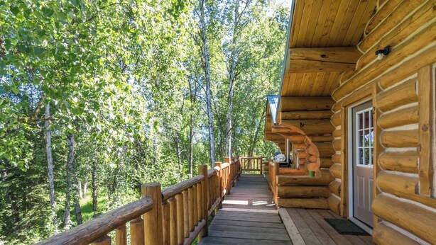 A wooden log cabin with a wooden deck leading to a door.