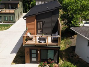 Ein zweistöckiges Haus mit Balkon, einer kleinen Veranda und einer Garage.