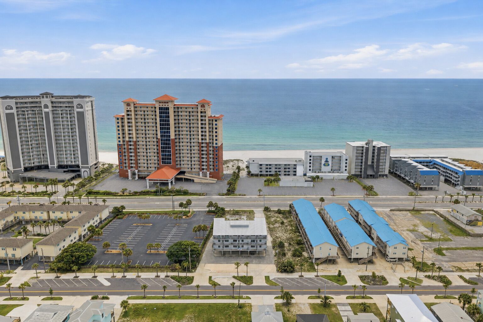 Ein Hotelkomplex an der Küste mit mehreren Gebäuden, einem Parkplatz und Blick auf den Strand und den Ozean.