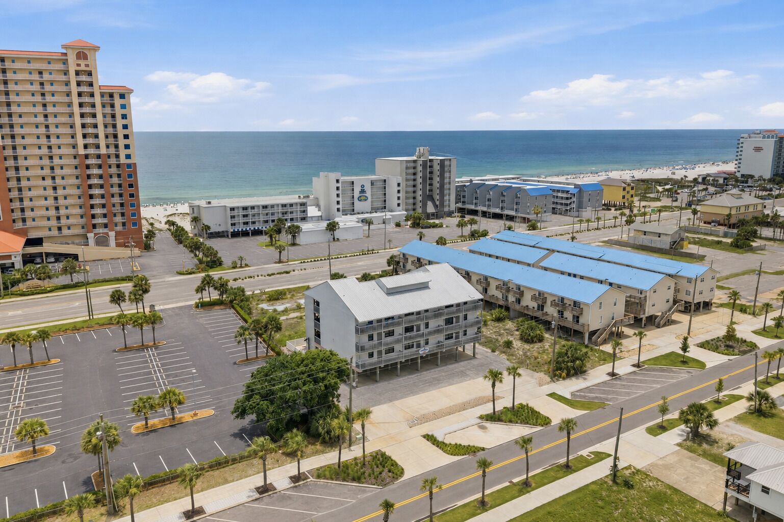 Ein Hotelkomplex an der Küste mit mehreren Gebäuden, Parkplätzen und Blick auf den Strand.
