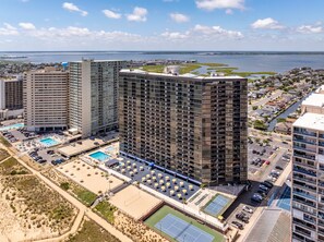 A high-rise hotel with multiple floors, a swimming pool, tennis courts, and a view of the water. - Oceanfront2Bed-Sleeps4-Pools-Sauna (Ocean City)