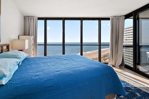 A hotel room with a large bed, a view of the beach, and a balcony with a glass door. - Oceanfront2Bed-Sleeps4-Pools-Sauna (Ocean City)