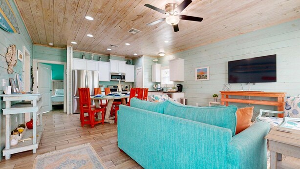 A cozy living room with a teal sofa, wooden ceiling, and a television. - SP3 Shared Pool, Pet Friendly, Parking for 3 (Port Aransas)
