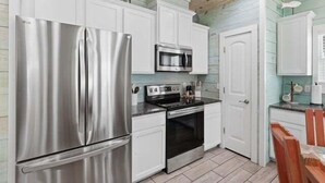 A compact kitchen with white cabinets, stainless steel appliances, and a wooden ceiling. - SP3 Shared Pool, Pet Friendly, Parking for 3 (Port Aransas)