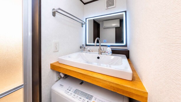 A compact bathroom with a sink, mirror, and washing machine. - A Family Friendly Spacious Villa - 1 min to Convenience Store (Edogawa City)